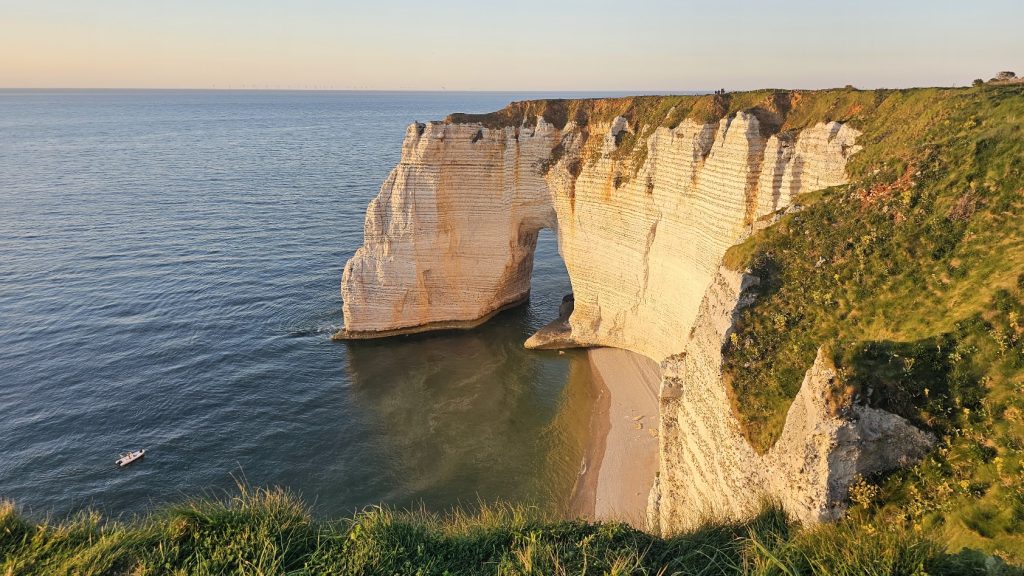 Vista da Manneporte, o maior arco natural de Étretat, nas falésias de giz branco da Normandia, iluminado pelo pôr do sol.