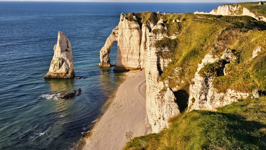 Falaise d'Aval em Étretat, com o arco natural Porte d'Aval e a Aiguille ao pôr do sol.