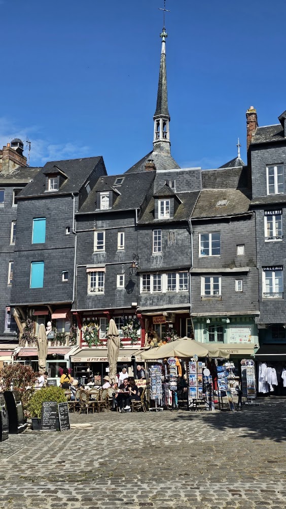 Casas históricas de Honfleur com fachadas de ardósia e torre de Sainte-Catherine ao fundo